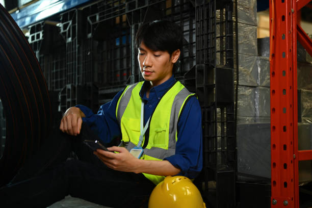 istock Male warehouse worker sitting on floor and using smartphone during break 1696744936