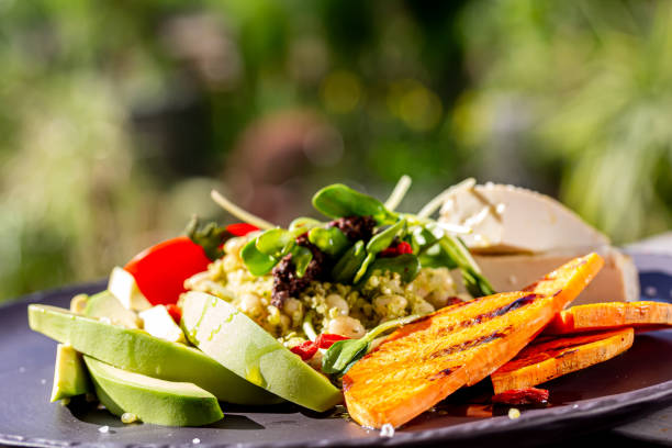 Healthy vegetarian salad with raw beetroot, carrot, arugula, avocado, orange, cheese and pumpkin seeds on white plate, top view.