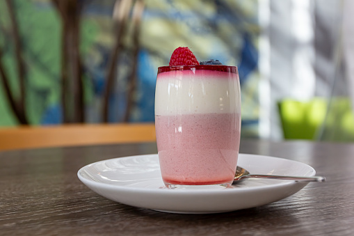 Sweet raspberry mousse in glass on grey wooden table