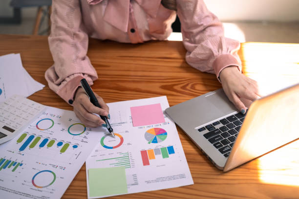 istock Female financier analyzing graphs and charts preparing report on wooden office desk 1696749946