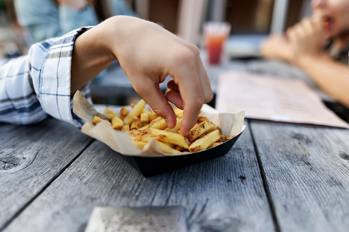 Teenagers have ordered French Fries for lunch and they are enjoying eating them. The fries are made from not peeled potatoes that saves a lot of waste.
Closeup of the fries on the plate. Hands reaching for French fries.
Shot With Canon R5