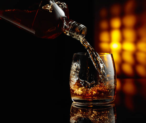istock Pouring whiskey from a bottle into a glass. 1696761035