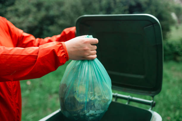 Caucasian woman sorting garbage, throwing a used paper bag in a small recycle bin at outdoor near a home . High quality photo