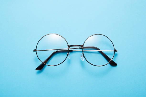 istock Glasses in round thin metal frame isolated on blue surface. 1696770307