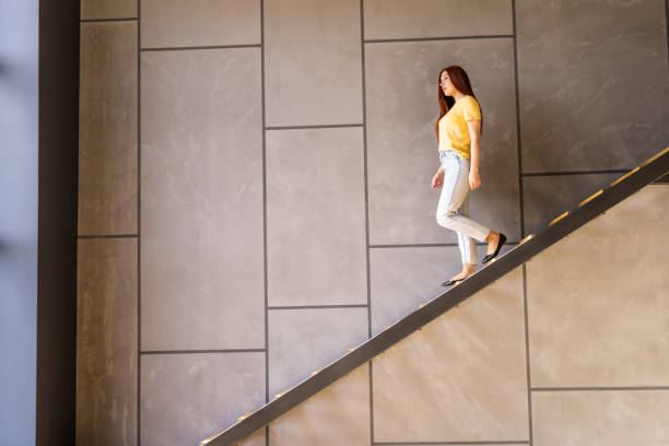 istock Young woman going down the stairs in modern house 1696777844
