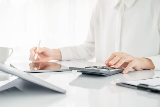 istock Modern business woman using calculator and tablet  in workstation. 1696790930