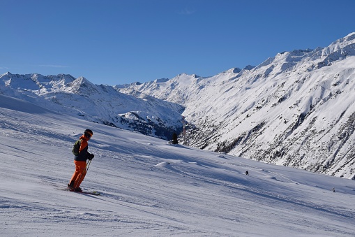 Skiers and snowboarders in Hochgurgl ski resort, backdropped by the Ötztal valley and the snow capped alpine mountains in Tyrol, Austria on a beautiful sunny day, perfect conditions for winter sports.