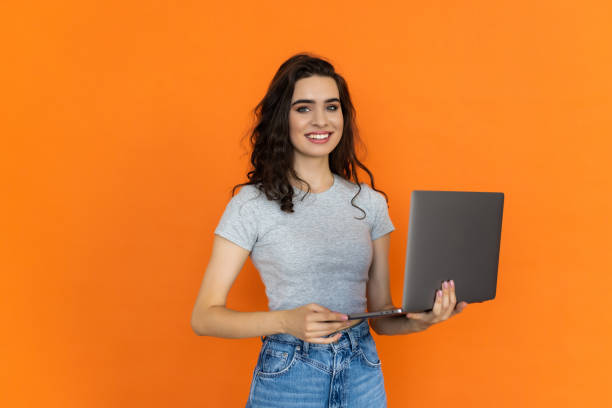 istock Young smiling freelancer copywriter student woman hold laptop browsing on yellow orange background 1696827757