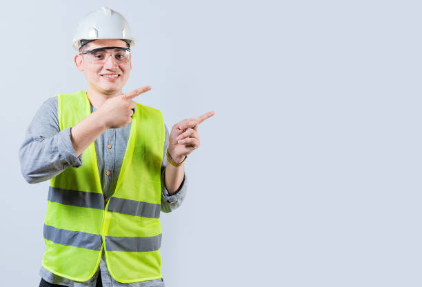 istock Cheerful engineer with helmet pointing aside isolated. Handsome engineer pointing an advertisement isolated 1696831783