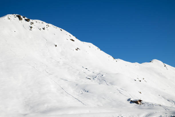 Tiny mountain hut in a snow landscape with clear sky near Davos, Switzerland