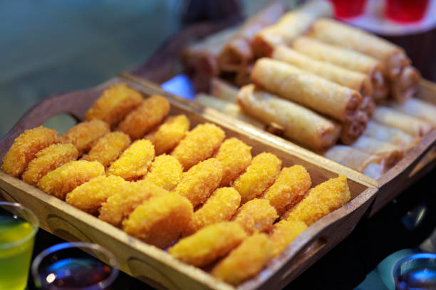 Deep-fried chicken nuggets and spring rolls served on a wooden tray on the buffet line