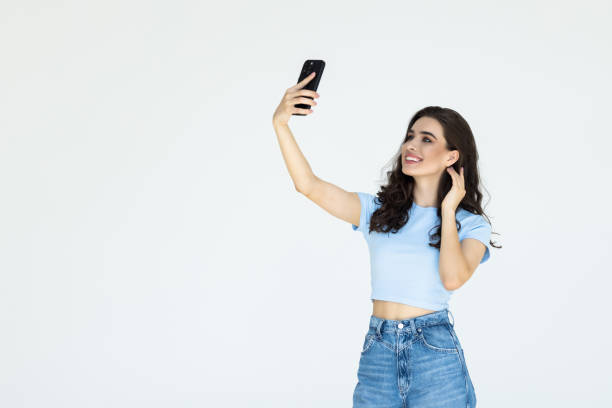 istock Smiling vlogger girl looking at mobile make video call, shooting vlog taking selfie on grey background 1696881840