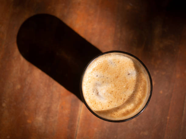 Close up from above a glass of tropical ice black coffee on the rustic wooden table, lowkey ambience, and with side light