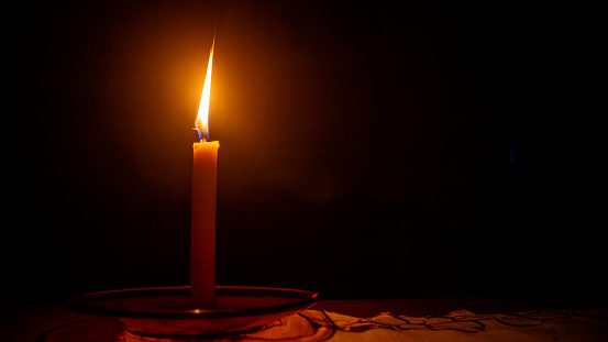 a burning candle against a dark background
