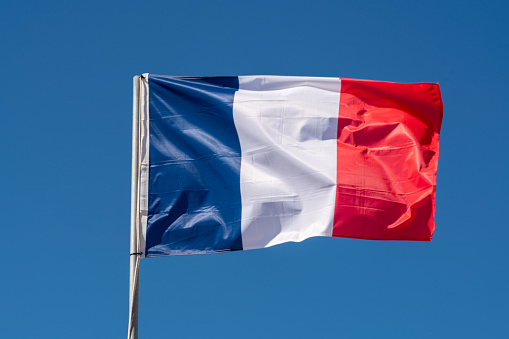 Close up of France Flag waving against clean blue sky, isolated and with clipping path mask.