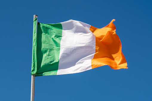 Close up of Ireland Flag waving against clean blue sky, isolated and with clipping path mask.