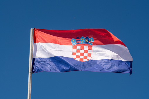 Close up of Croatia Flag waving against clean blue sky, isolated and with clipping path mask.