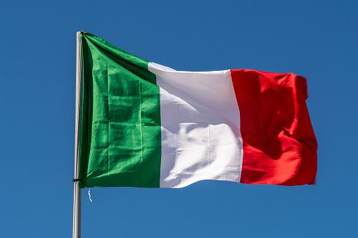 Close up of Italy Flag waving against clean blue sky, isolated and with clipping path mask.