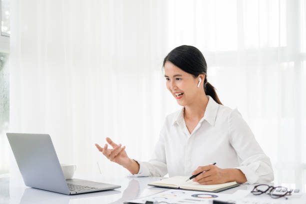 istock Asian business woman employee or executive manager using computer looking at laptop and talking leading hybrid conference remote video call virtual meeting or online training working in office. 1696915861