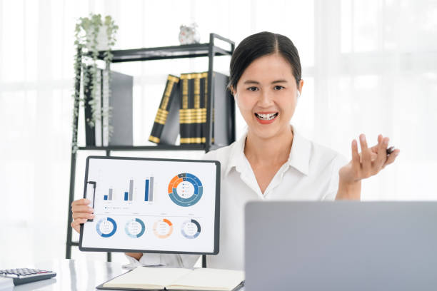 istock Asian business woman employee or executive manager using computer looking at laptop and talking leading hybrid conference remote video call virtual meeting or online training working in office. 1696916957
