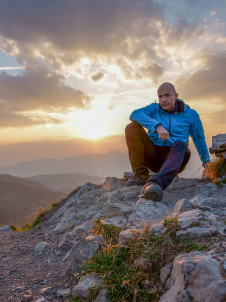 istock Man sits on edge cliff on the picturesque sunrise background 1696918125