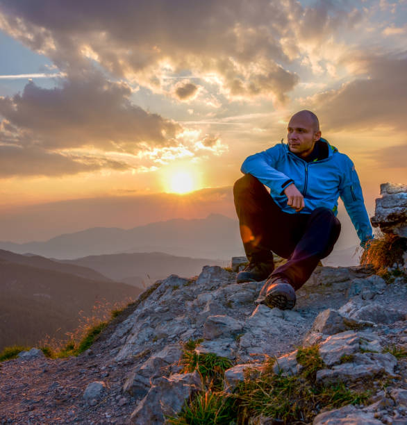 istock Man sits on edge cliff on the picturesque sunrise background 1696918128