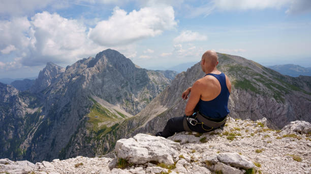 istock Young man sits on the cliff edge in Kamnik-Savinja Alps 1696923081