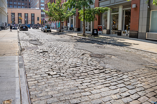 Wooster Street, Manhattan, New York, USA - August 8th 2023:  Cobblestones and asphalt repair in an old New York street
