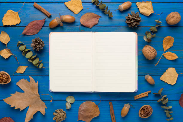 istock Autumn leaves with notebook on wooden background, top view 1696942906