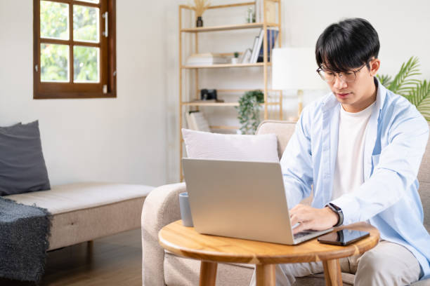 istock Close up portrait of handsome man working from home office taking reading and writing notes in note pad while working on laptop computer casual businessman entrepreneur focused doing research 1696952037