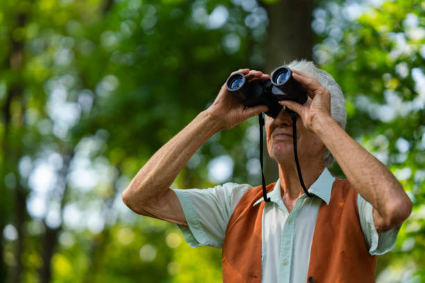 istock Senior man spending free time outdoors in nature, watching forest animals through binoculars. 1696978770