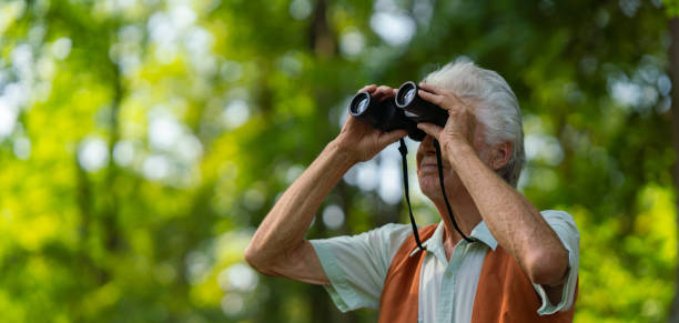 istock Senior man spending free time outdoors in nature, watching forest animals through binoculars. 1696980883