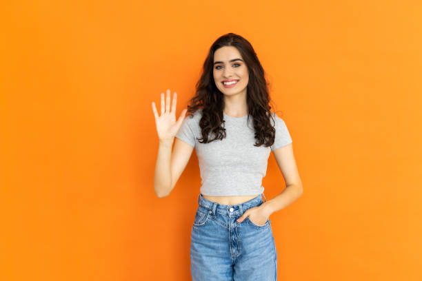 istock Happy young woman giving high five on orange background, space for text 1697007907