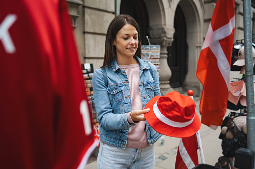 Female tourist standing by the street shop, buying local souvenirs in the city of Copenhagen, Denmark