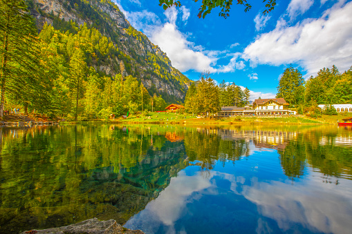 The idyllic lake Fallersee in Vorarlberg in the Austrian alps. There are hills with forest and their reflection in the  background.