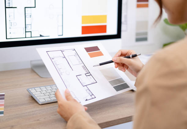 istock Young asian female interior designer or architect working on creative project with drawing, material sample and computer in office. Business of Real estate, home decoration & renovation concept. 1697055619
