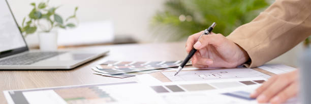 istock Young asian female interior designer or architect working on creative project with drawing, material sample & laptop computer in office. Business of Real estate, home decoration & renovation concept. 1697059284