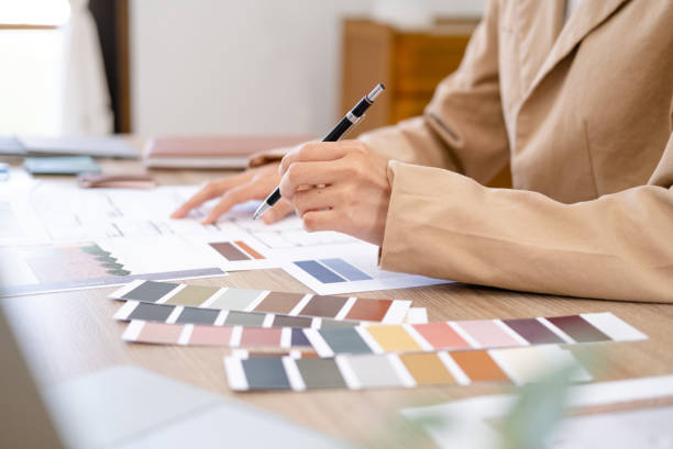 istock Young asian female interior designer or architect working on creative project with drawing, material sample in office. Business of Real estate, home decoration and renovation concept. 1697064219
