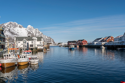Port of fishing village Henningsvær in the Lofoten Island. Lots of fishing boats on sunny winter day against rocky mountain.