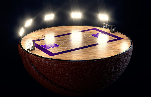 A basketball ball split in half revealing a marked wooden court with hoops at night under illuminated floodlights - 3D render