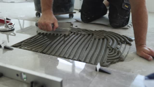 Professional tiler working with adhesive