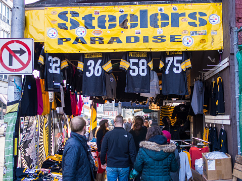 People shopping at a winter street market featuring sports clothing merchandise in Pittsburgh's Strip District.