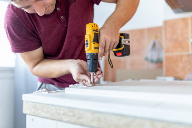 Man holding cordless screwdriver machine and screws lie for screwing a screw assembling furniture at home Close up of man assembling furniture by using cordless screwdriver. Wood door hinge installation drill stock pictures, royalty-free photos & images