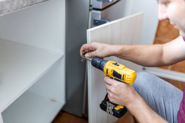 istock Man using cordless screwdriver machine and screws lie for screwing a screw assembling furniture for new kitchen 1697109495