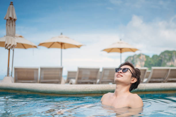 istock Asian men sunbathing at beach side pool 1697127813