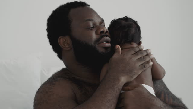 African father holding his baby at home.