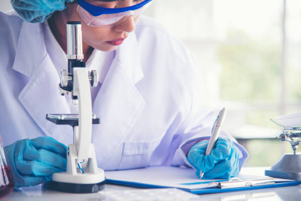 istock Researcher biology chemistry. Asian Female technician laboratory using microscope blood test. Asian Woman scientist hand write note research in medical lab look at science microscope medical test 1697138841