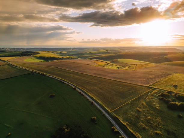 aerial drone view of road running through beautiful south downs landscape in southeast england at golden hour - southeast england imagens e fotografias de stock