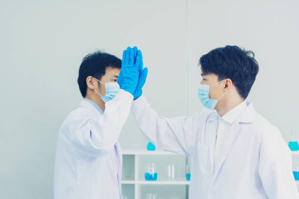 dos científicos asiáticos del equipo de cinco socios se dan la mano. science men investiga el experimento de la ciencia química. dos hombres compañeros de trabajo de biotecnología saludo de éxito en el laboratorio. trabajo en equipo exitoso - artificial true exam blue fotografías e imágenes de stock