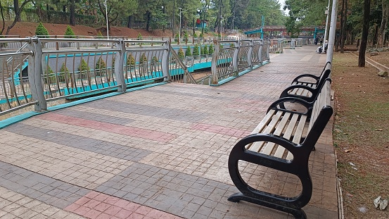 the atmosphere of a quiet public park with two long benches with con bloc floors in various colors